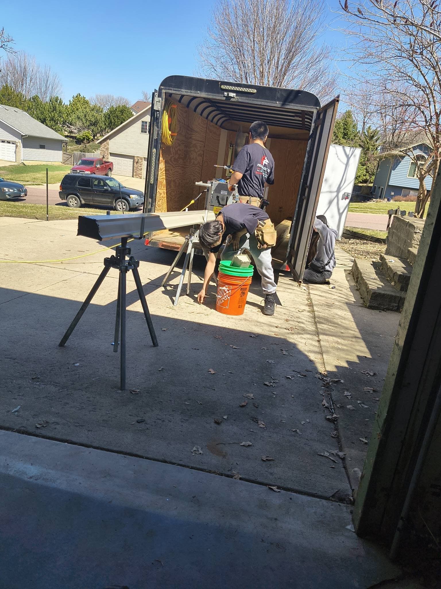 Crew members in Precision Gutters shirts forming a gutter run at the trailer