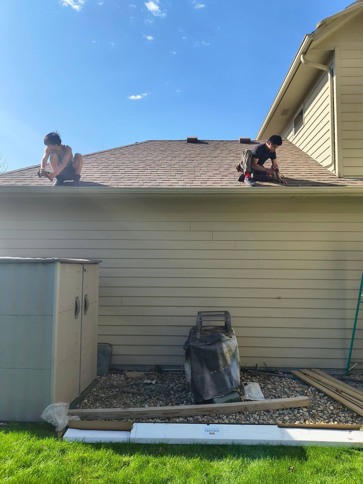 Two Precision Gutters crew members on a roofline fastening a new gutter run at the eave